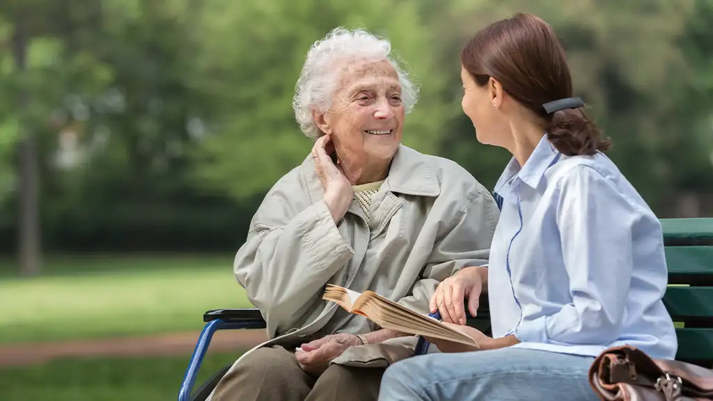 Woman and care giver reading a book outside